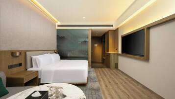 A modern hotel room with a bed, bedside table, and a TV mounted on the wall.