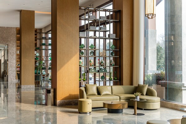 A modern lobby with a leather sofa, a coffee table, and a bookshelf filled with decorative items.