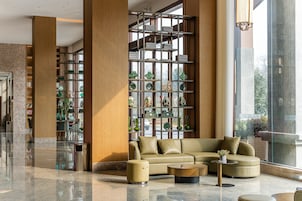 Un lobby moderno con un sofá de cuero, una mesa de centro y una estantería llena de objetos decorativos.