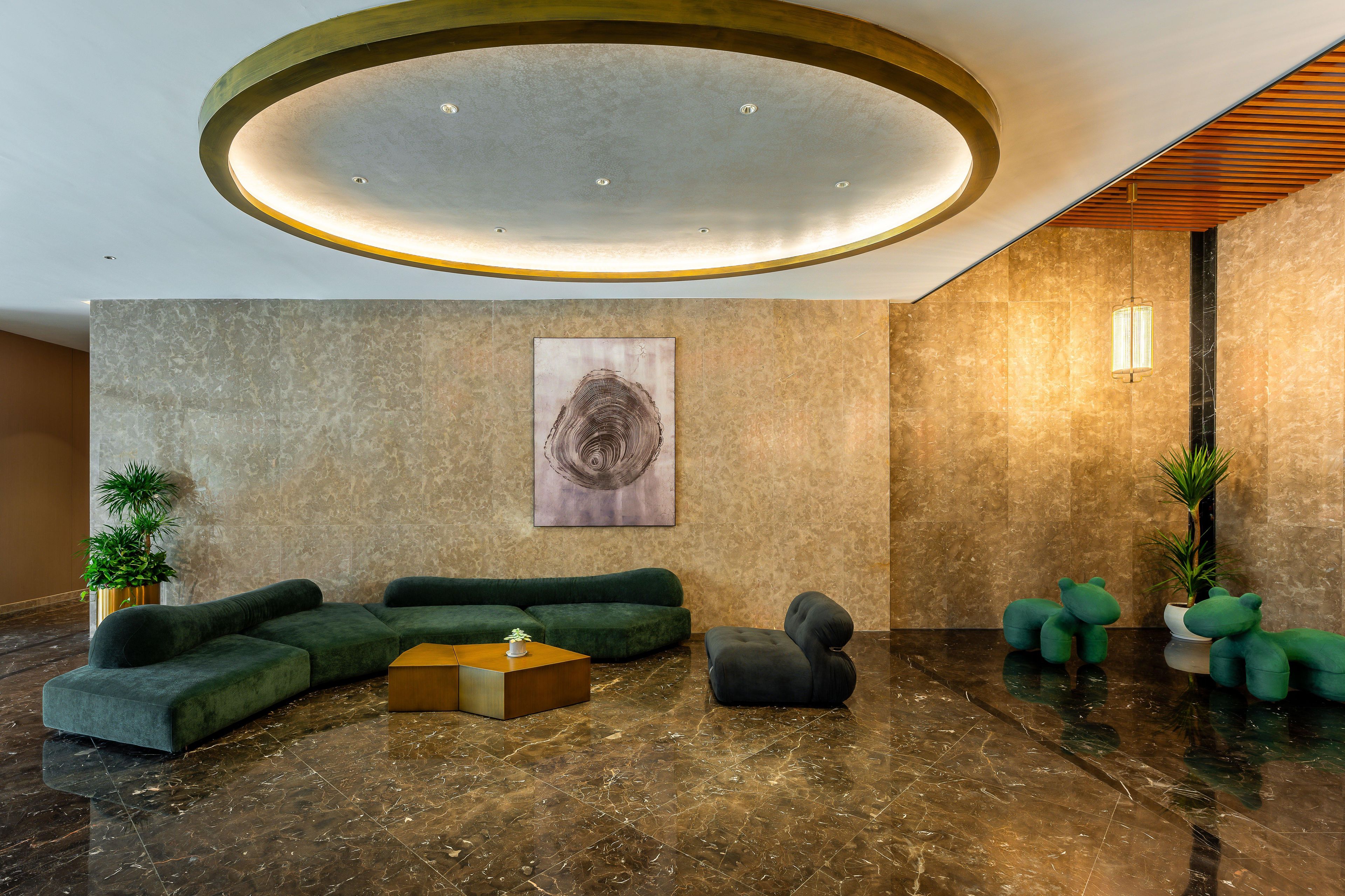 Un hall con un sofá seccional verde, una mesita redonda y una planta en maceta.
