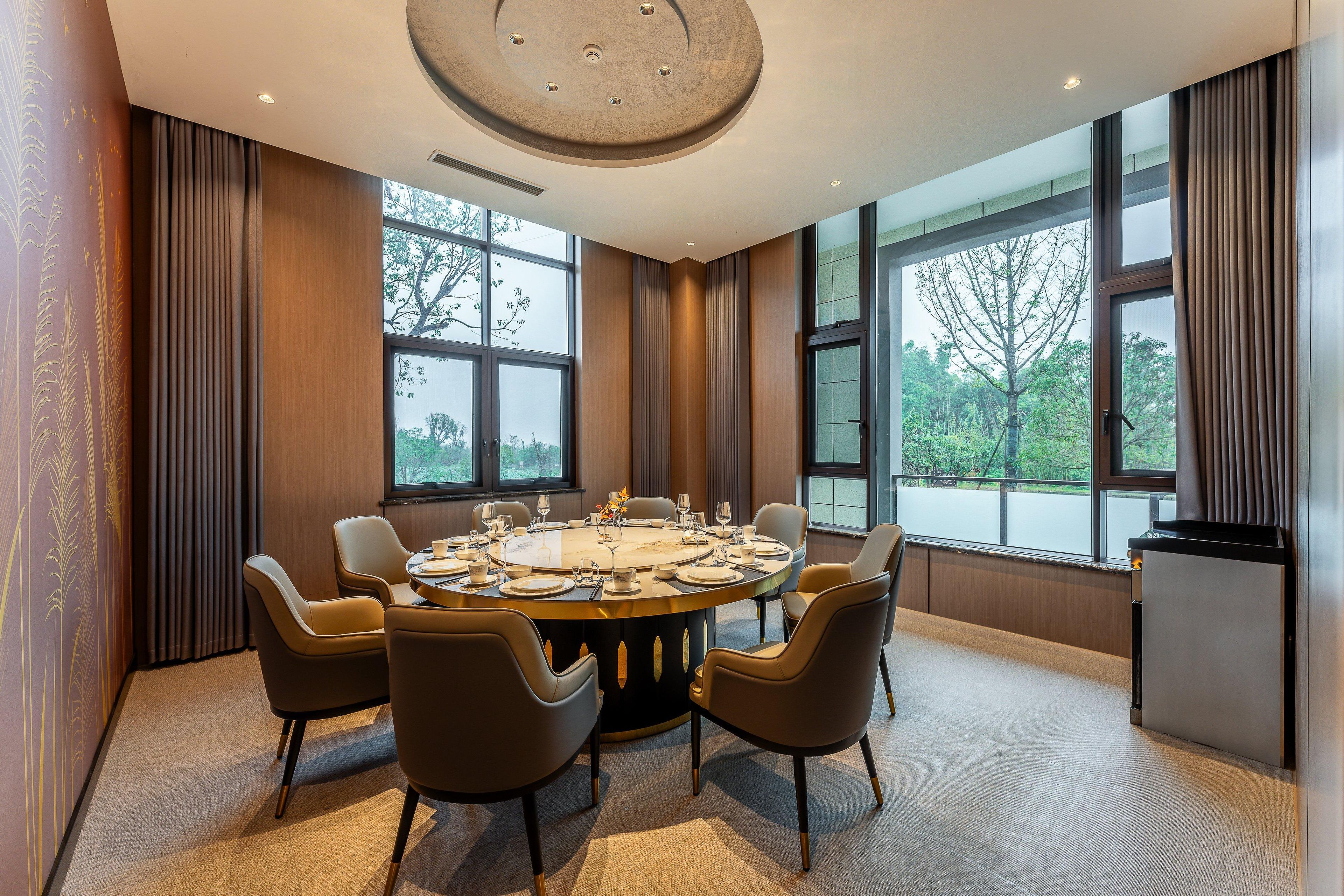 Un comedor moderno con una mesa redonda para seis personas, ventanas amplias y vista a los árboles.