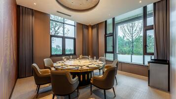 Un comedor moderno con una mesa redonda para seis personas, ventanas amplias y vista a los árboles.