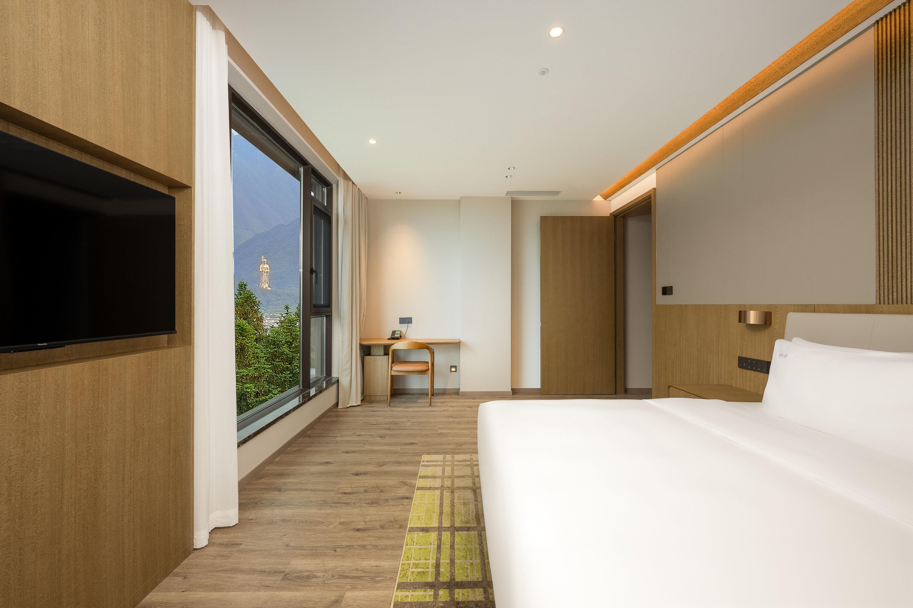 Una habitación de hotel moderna con una cama grande, un escritorio y un televisor.