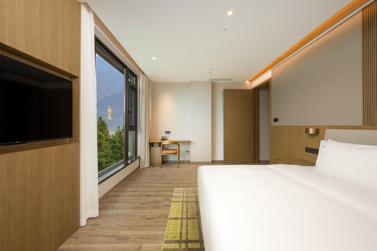 A modern hotel room with a large bed, a desk, and a TV.