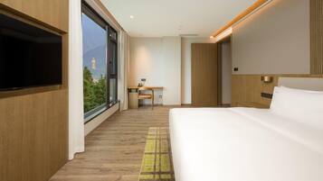 Una habitación de hotel moderna con una cama grande, un escritorio y un televisor.
