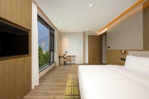 Quarto de hotel moderno com uma cama grande, uma escrivaninha e uma televisão.