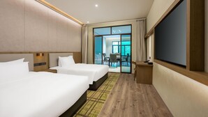 Habitación de hotel con dos camas, televisión y vista al comedor.