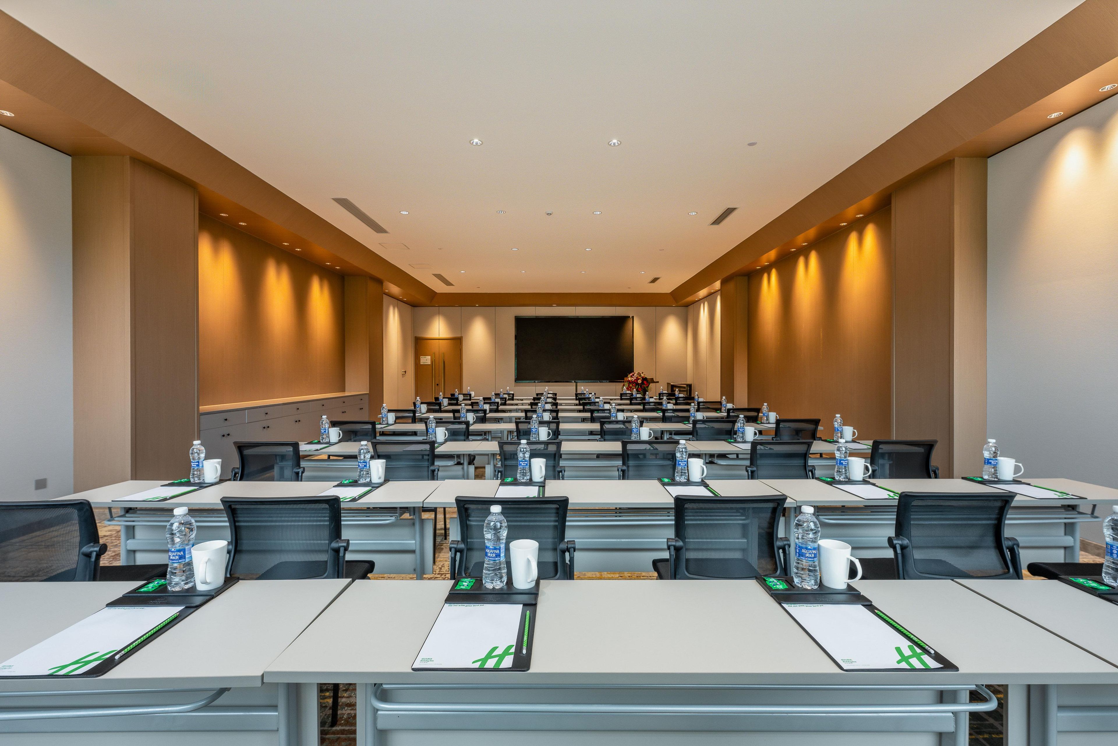 A conference room with rows of tables, chairs, and water bottles.