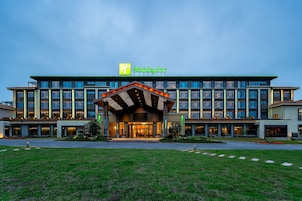Un hotel Holiday Inn con fachada moderna, varios pisos y una entrada bien iluminada.
