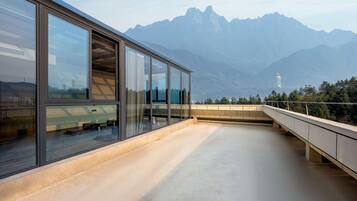 Een modern gebouw met grote glasramen met uitzicht op een bergachtig landschap.