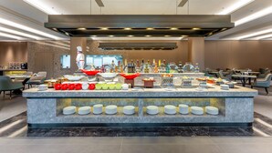 Una presentación de buffet moderna con diversos alimentos y bebidas, una encimera de mármol impecable y un diseño interior contemporáneo.