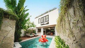 Une maison moderne dotée d’une piscine, de mobilier d’extérieur et d’une végétation luxuriante.
