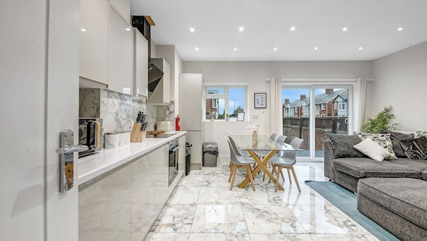 A modern kitchen with white cabinets, a marble backsplash, and a dining area with a glass table and chairs. - 4 Br & 4 Bath Cowley House Sleep 10 With Parking (Oxford)