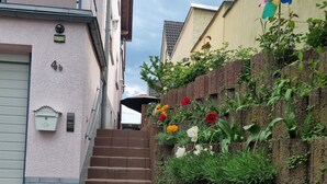 Un edifici residencial amb una escala de maó que porta a una porta, una closca de correu i una jardinereta a la paret.