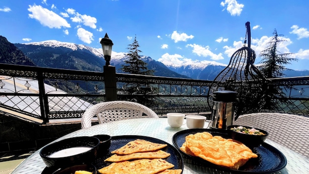 Une table avec de la nourriture et des boissons sur un balcon offrant une vue sur la montagne.