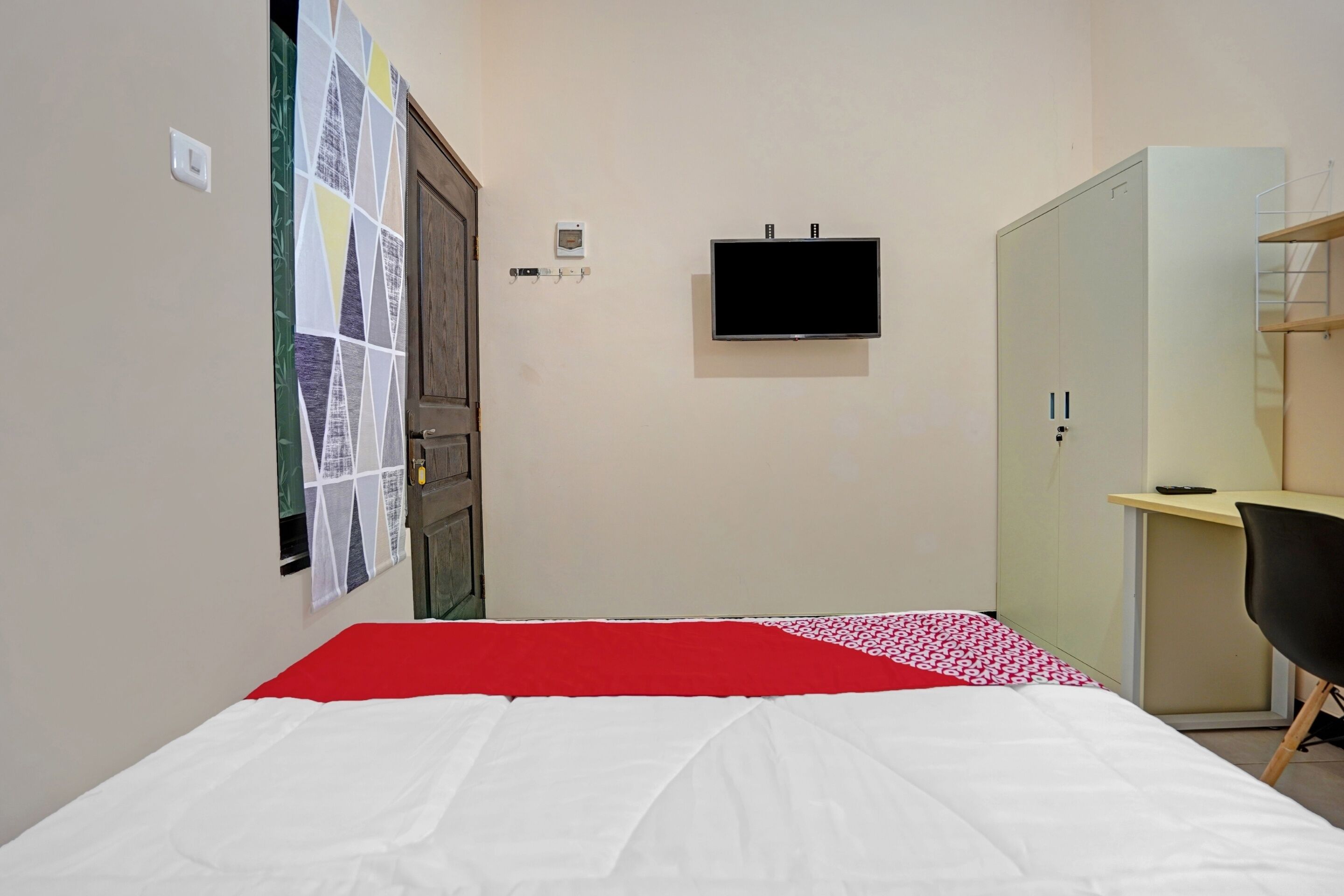 A bedroom with a bed, a TV, a wardrobe, and a desk.