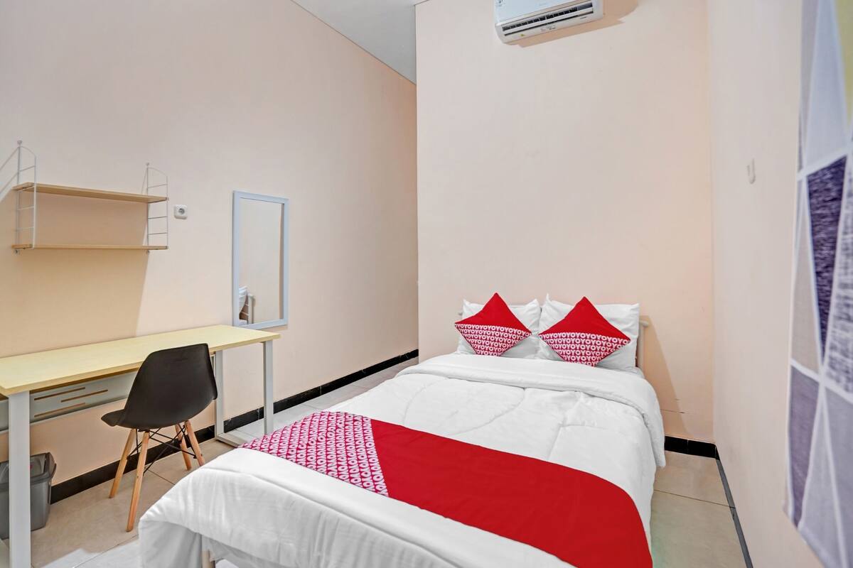 Une chambre d’hôtel avec un lit, un bureau, une chaise et un miroir.
