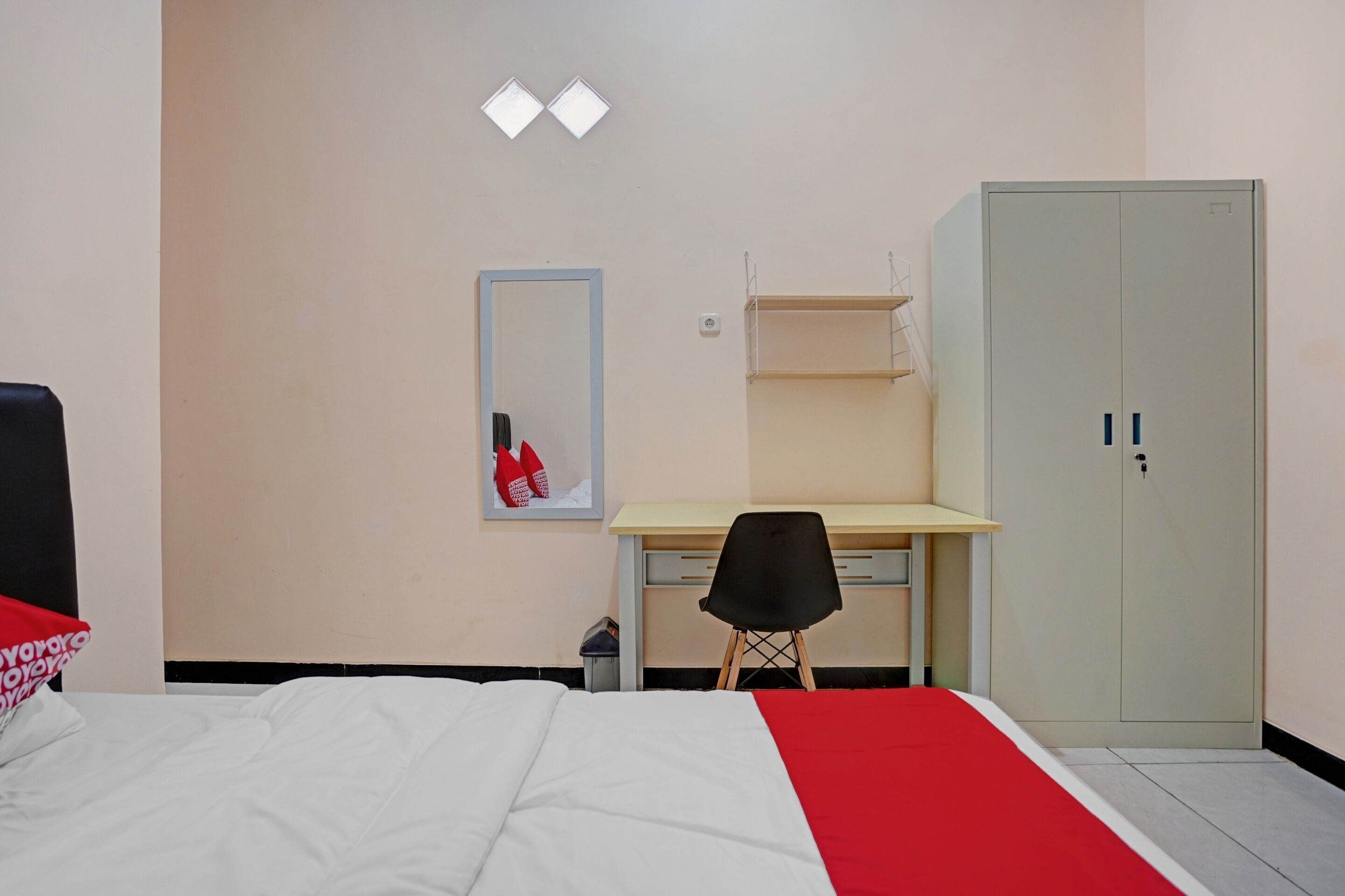 Een slaapkamer met een bed, een bureau, een stoel, een kledingkast en een spiegel.