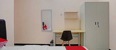 A bedroom with a bed, a desk, a chair, a wardrobe, and a mirror.