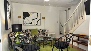 Una sala de estar con un sofá, dos sillones, una mesa de centro y un cuadro en la pared.