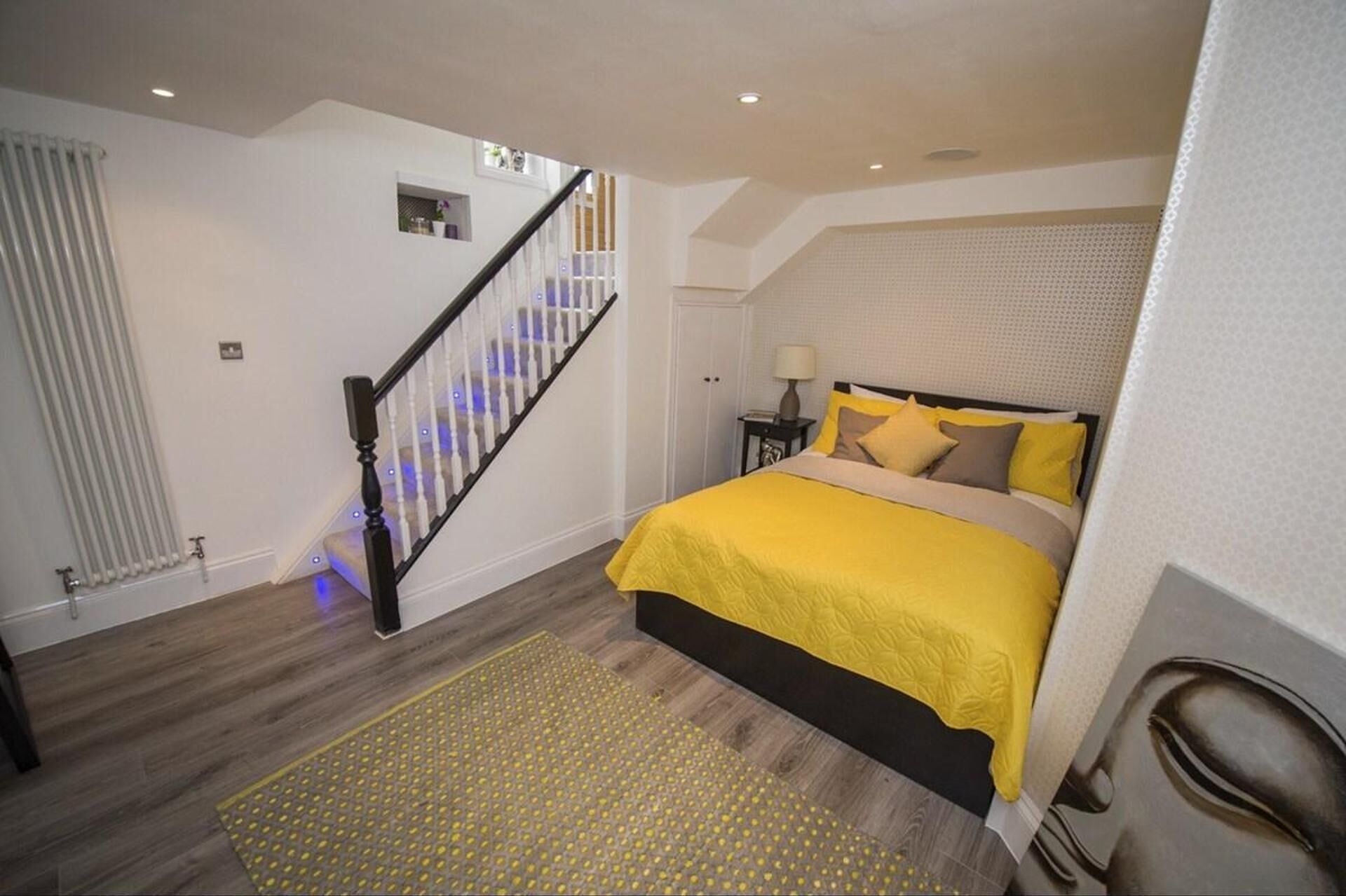 A bedroom with a bed, a staircase, and a radiator.