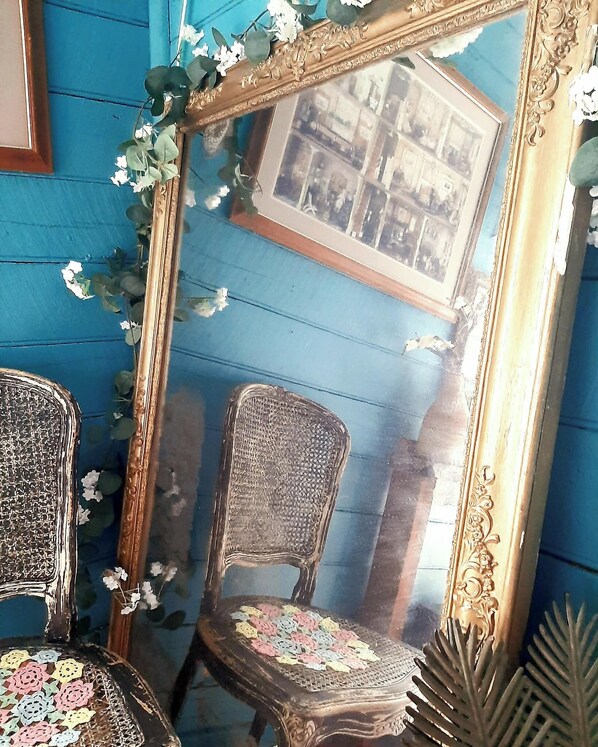 Una habitación con pared azul, un espejo y dos sillas.