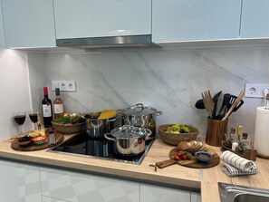 Eine Küche mit Marmorarbeitsplatten, Edelstahlgeräten und diversen Kochutensilien.
