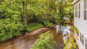 Ein Fluss fließt durch ein bewaldetes Gebiet, auf der rechten Seite steht ein Haus.