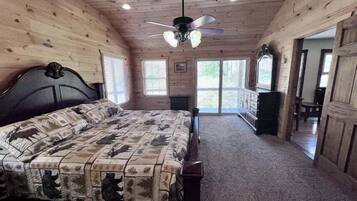 A bedroom with a bed, a ceiling fan, and a view of the outdoors through a sliding door.