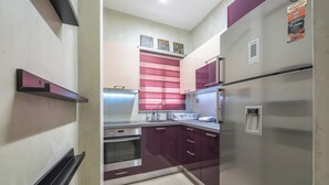 A compact kitchen with stainless steel appliances, a built-in oven, and a refrigerator. - Stylish 2 Bd Urban Retreat Near Panormou Metro (Athina)