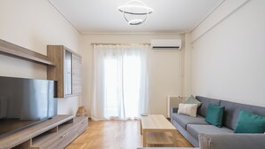 A modern living room with a flat-screen TV, wooden entertainment unit, grey sofa, and a wooden coffee table. - Stylish 2 Bd Urban Retreat Near Panormou Metro (Athina)