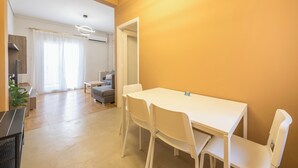 A modern living room with a white dining table and chairs, a grey sofa, and a wooden floor. - Stylish 2 Bd Urban Retreat Near Panormou Metro (Athina)