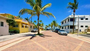 A street lined with palm trees and buildings, including a yellow building with a sign. - Sand Vibes Studio Steps to Beach• Pool & Parking (Hollywood)