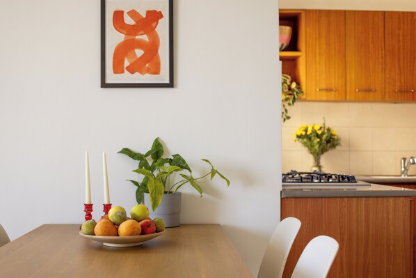 A dining table with a fruit bowl, candles, and a potted plant. - Old North Green Oasis by Sea N' Rent (Tel Aviv)