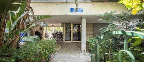 A narrow pathway leading to a building entrance with a blue sign indicating the number 2.