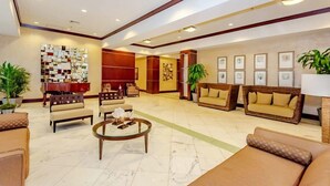 A spacious lobby with a piano, sofas, and a coffee table. - Beachfront Paradise - Spectacular Ocean Views - Great Location & Amenities! (Sunny Isles Beach)