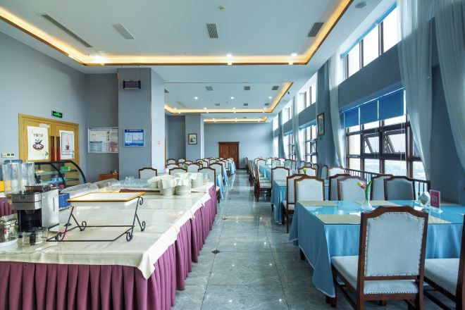 A conference room with long tables, chairs, and a projector screen.