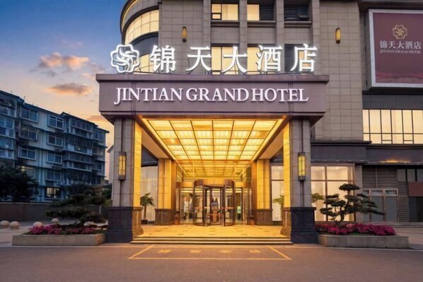 Jintian Grand -hotellin sisäänkäynti, jossa on pyörivät ovet ja valaistu sisäänkäyntialue.