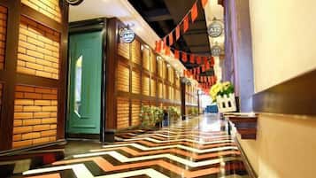 A hotel corridor with a chevron-patterned floor, wooden paneling, and a green door.