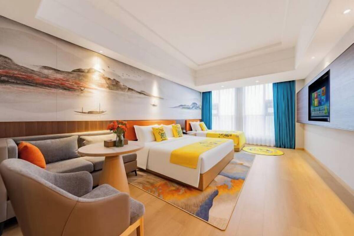A modern hotel room with a bed, sofa, and a small table.