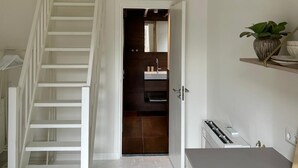 Een moderne keuken met een inbouwoven, een wit aanrecht en een RVS-spoelbak.