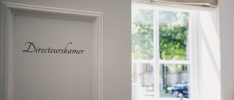 A room with a white door labeled "Directeurskamer" and a window with a view of the street outside.