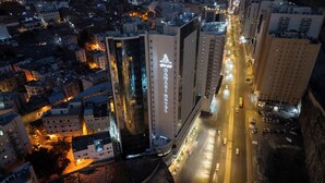 A high-rise hotel with a prominent sign, surrounded by urban buildings and a busy street.