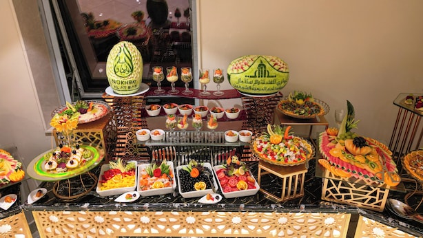 A buffet with various dishes and drinks, including a cake with Arabic writing.