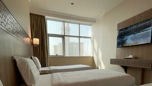 A hotel room with two beds, a TV, a window with a city view, and a decorative wall panel.