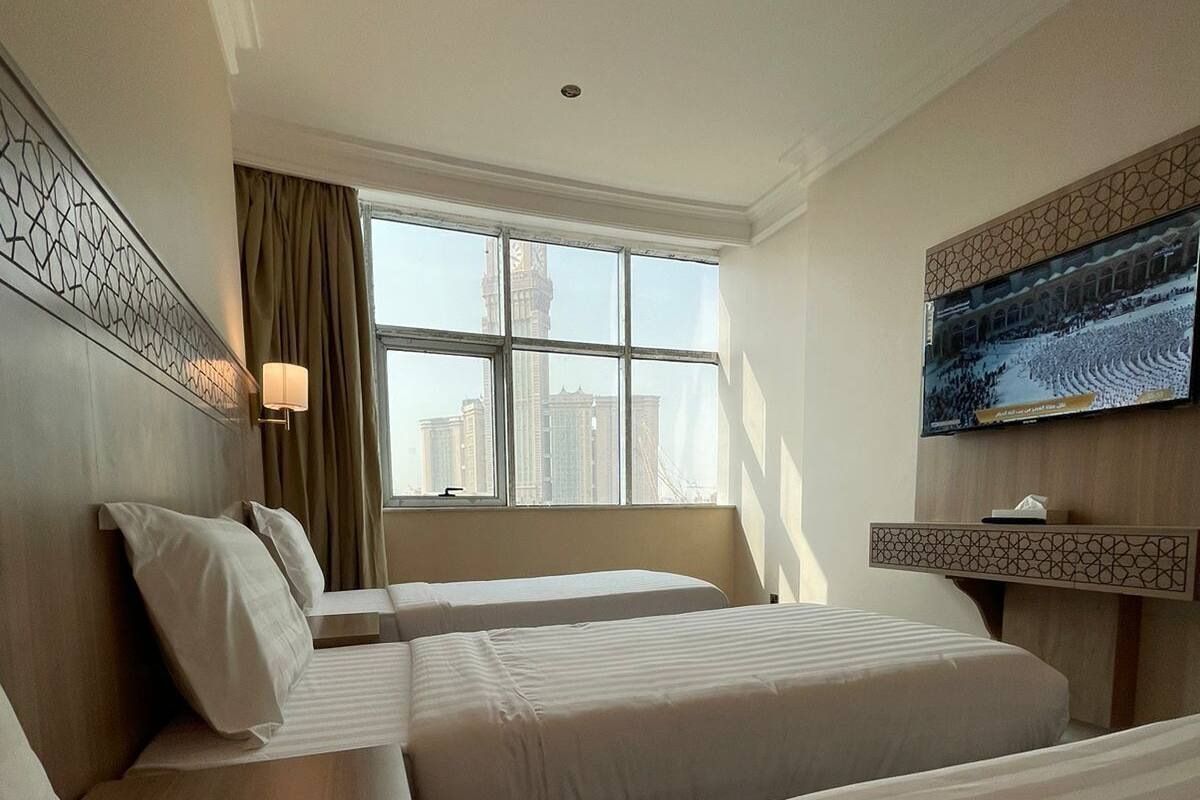 Habitación de hotel con dos camas, televisión, ventana y vista a la ciudad, además de un panel decorativo en la pared.