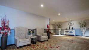 A spacious lobby with two armchairs, a small table, and a decorative mirror on the wall. - Borui Business Hotel (Tongxiang)