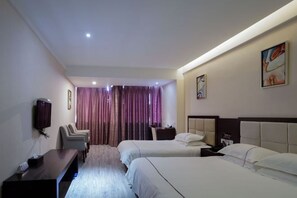 Quarto de hotel com duas camas, uma escrivaninha, televisão e janela com cortinas.