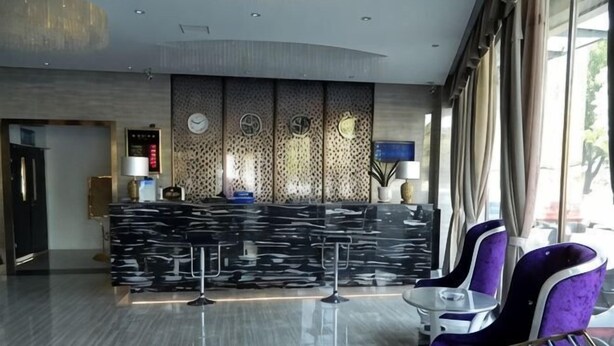 A reception area with a marble counter, purple chairs, and a large window. - Borui Business Hotel (Tongxiang)