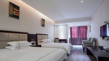 Ein Hotelzimmer mit zwei Betten, einem Fernseher, einem Schreibtisch und einem Stuhl.